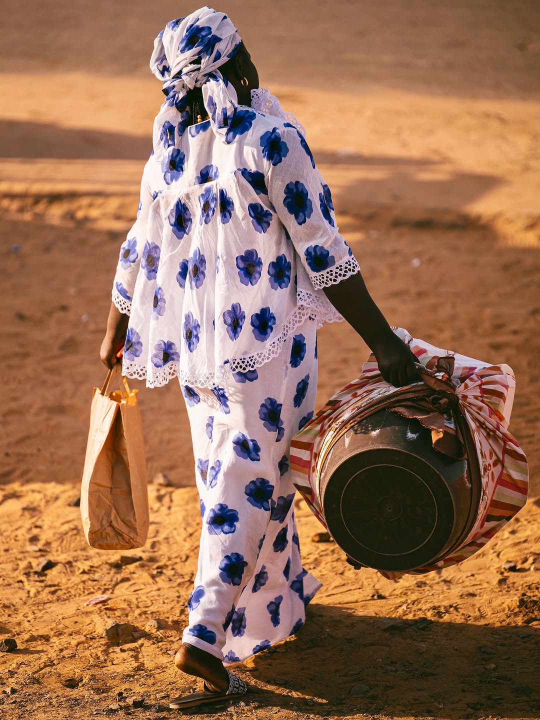 Femme sénégalaise en tenue traditionnelle wax à motifs fleuris, lumière dorée