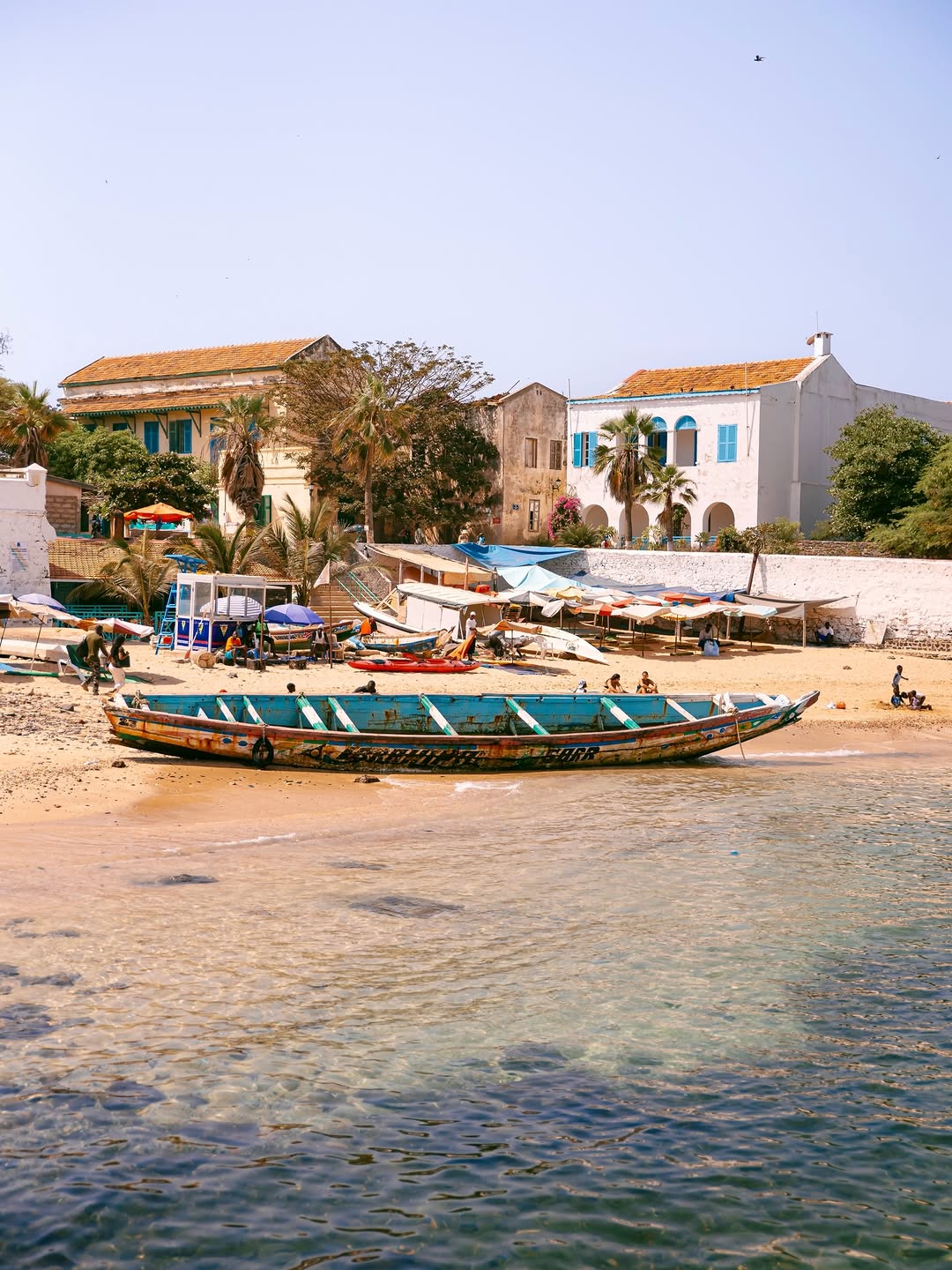 Pirogue de pêche colorée et maisons coloniales pastel sur la plage de l'île de Gorée, Sénégal