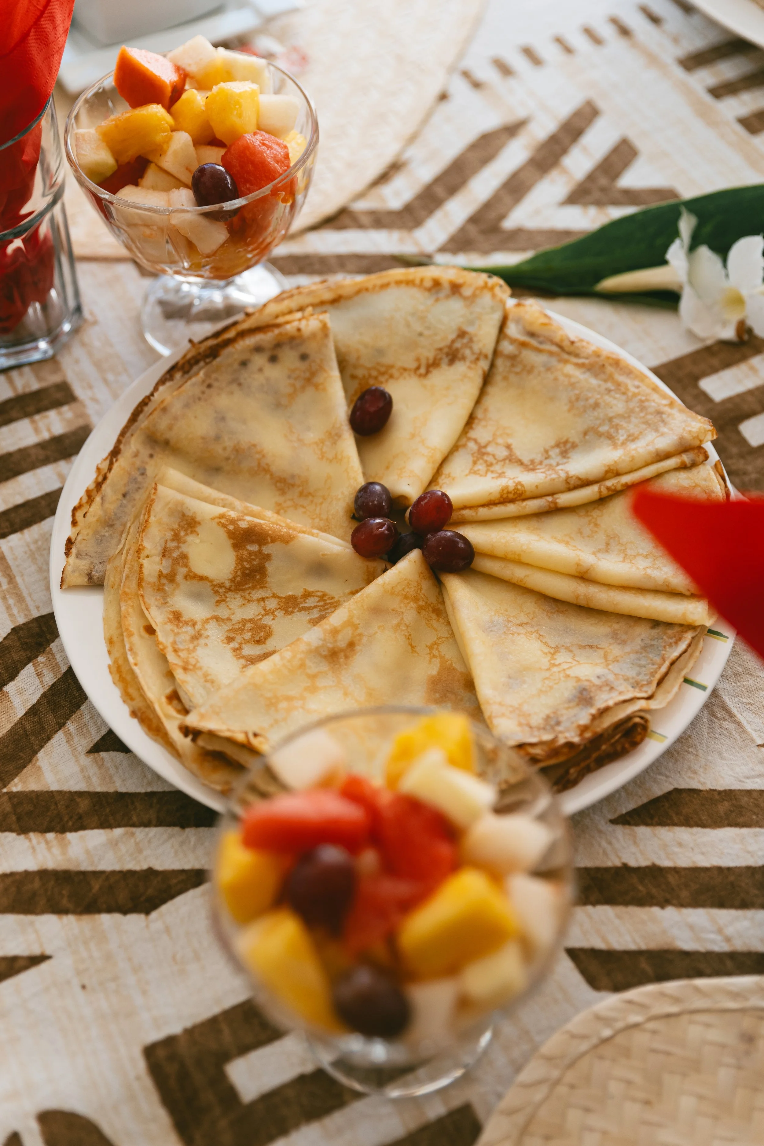 Crêpes de Rose et deux coupelles de salade de fruits sur nappe africaine